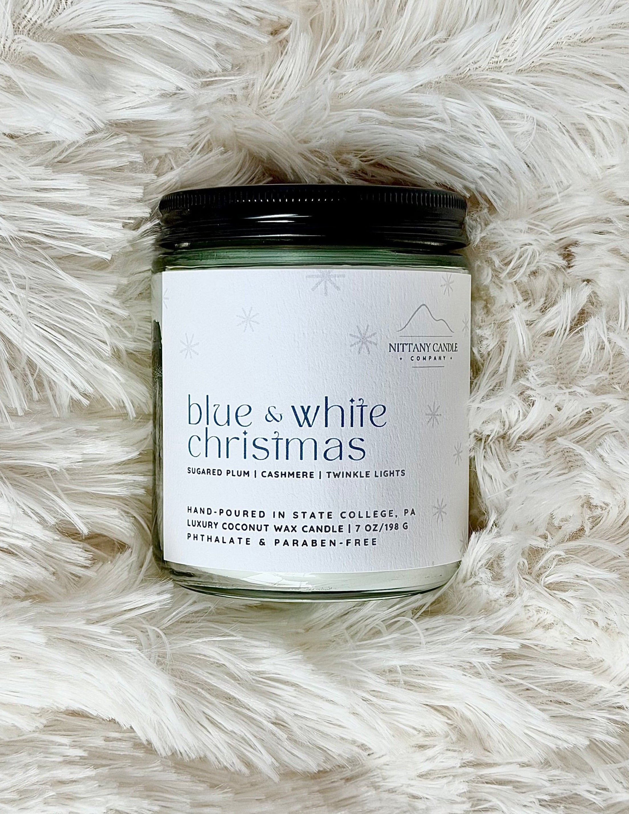 PENN STATE THEMED Candle jar labeled 'Blue & White Christmas' on a fluffy white surface