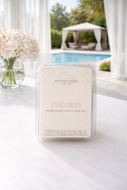 Nittany Candle Co. 'Cabana' wax melt on a white surface with a pool and flowers in the background