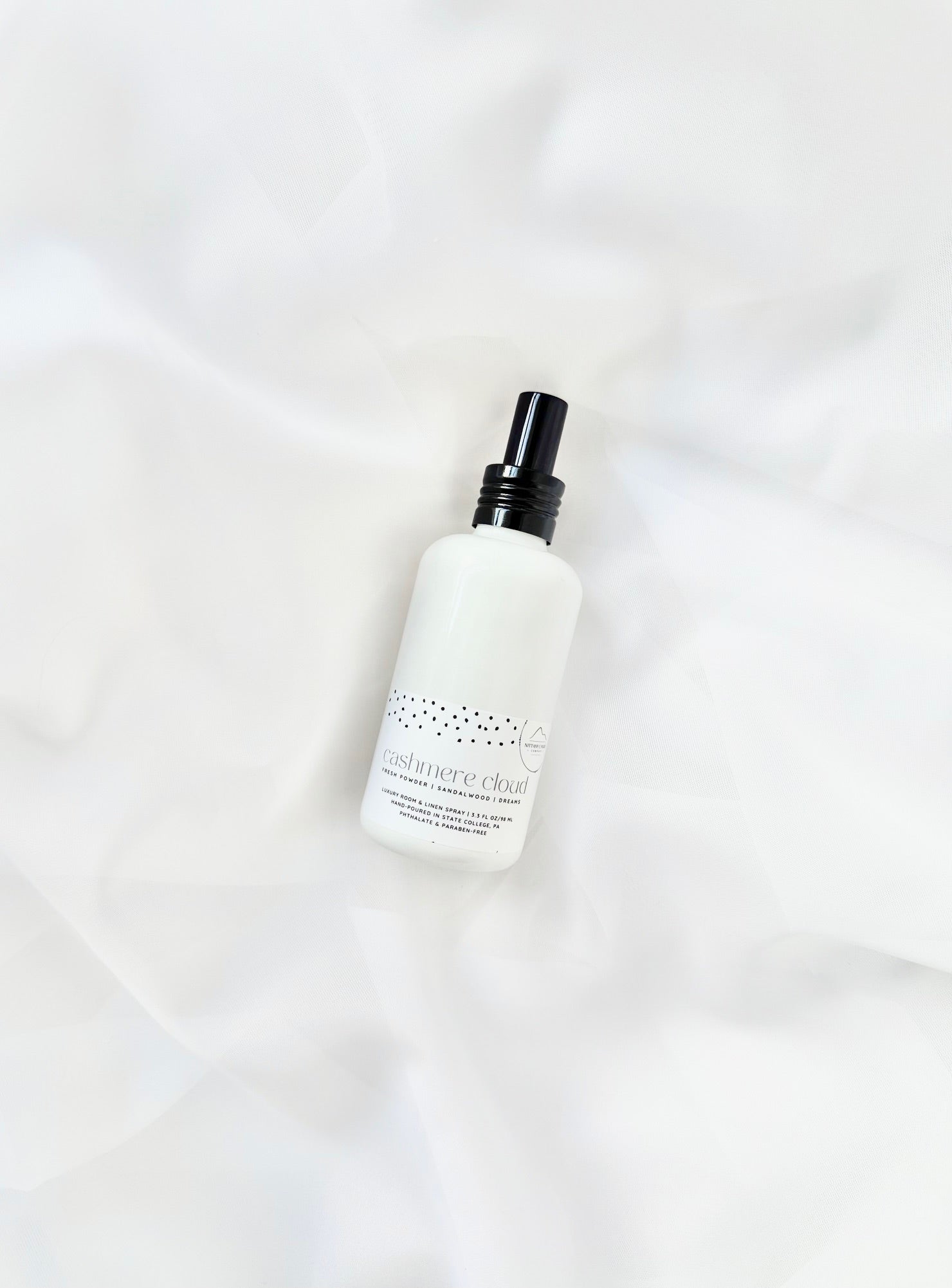 White room and linen spray bottle with black cap on white fabric background