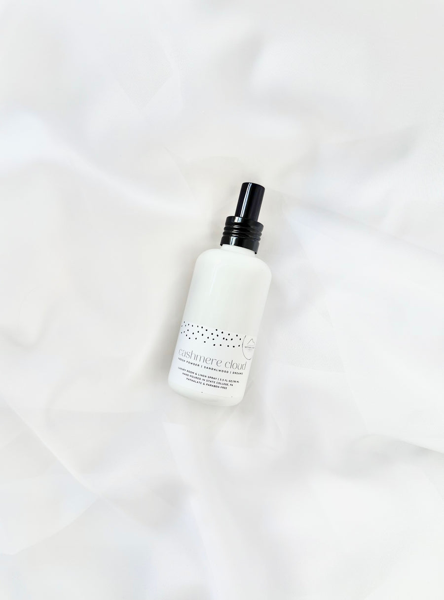White room and linen spray bottle with black cap on white fabric background