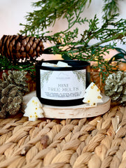 Mini tree wax melts labeled 'Mini Tree Melts' on a woven surface with greenery and pinecones.