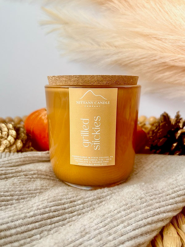 NITTANY CANDLE COMPANY wood wick candle with a cork lid on a textured surface with decorative elements