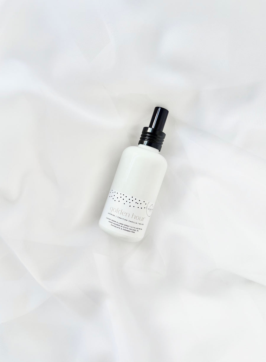Nittany Candle Co white room spray bottle with black cap on white fabric background