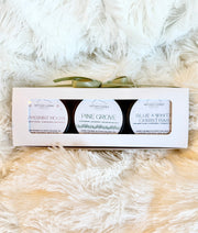 Set of three christmas candles in a gift box with a bow on a fluffy white surface