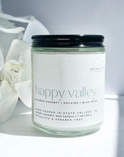 Penn State gift candle jar labeled 'happy valley' with a white orchid in the background