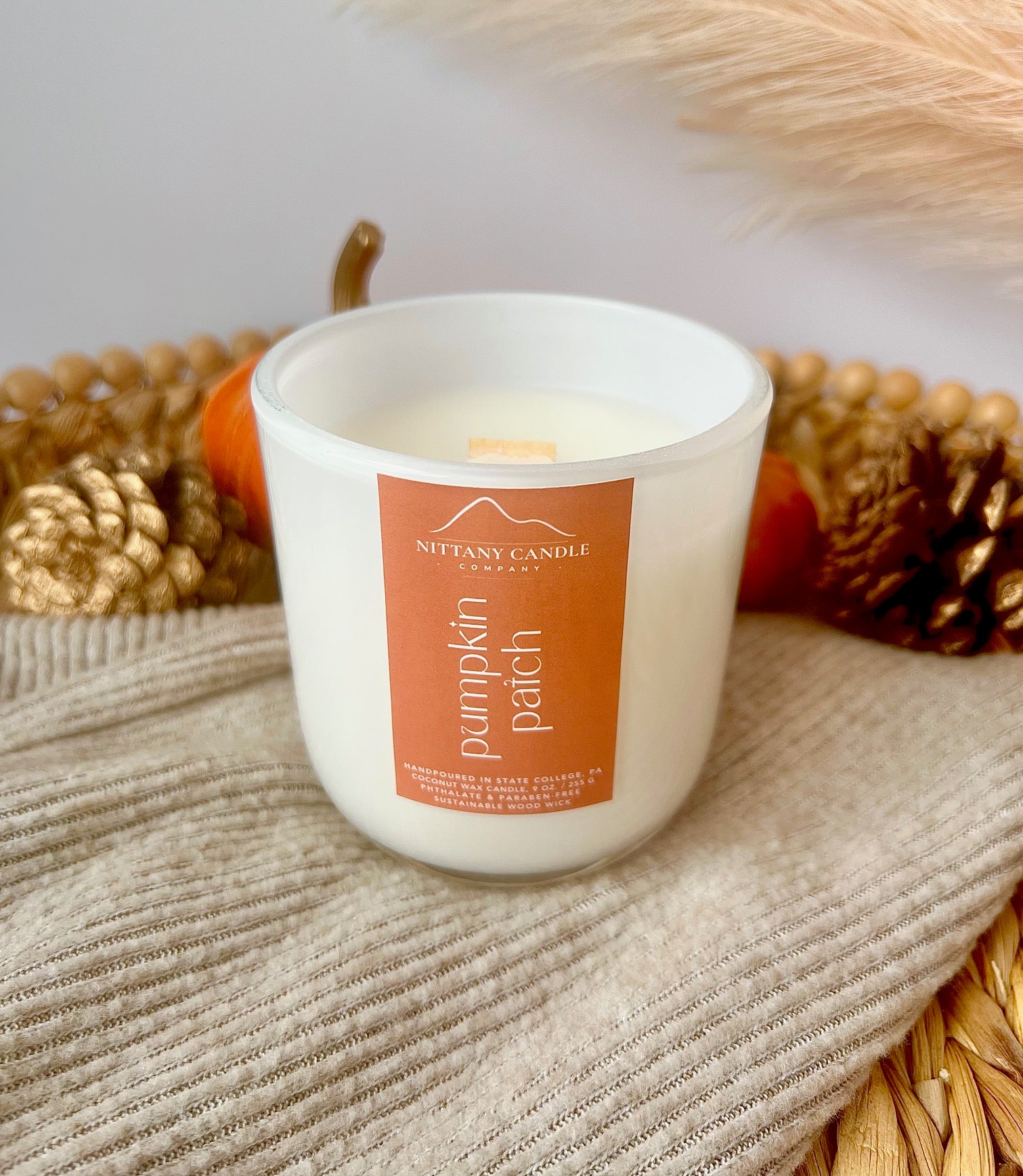 Nittany Candle Company pumpkin patch candle on a textured surface with decorative elements.