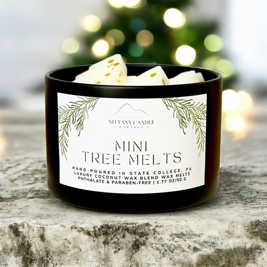 Black container of mini tree melts with a label on a wooden surface, Christmas tree in the background