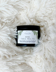 Jar of Christmas-themed mini evergreen tree melts on a fluffy white surface