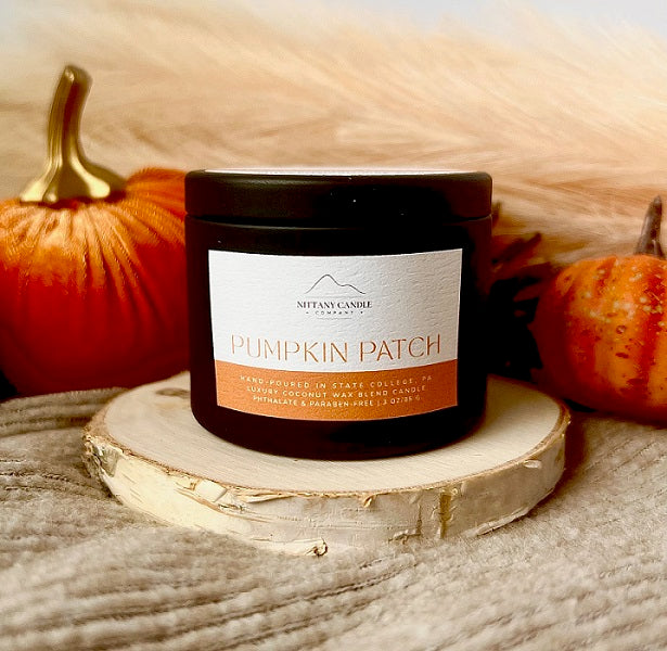 Nittany Candle Company pumpkin candle labeled 'Pumpkin Patch' on a wooden surface with pumpkins in the background