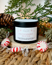 Nittany Candle Company Peppermint Mocha candle with peppermint candies and Christmas decor on a woven surface