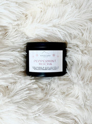 Candle labeled 'Peppermint Mocha' on a fluffy white surface