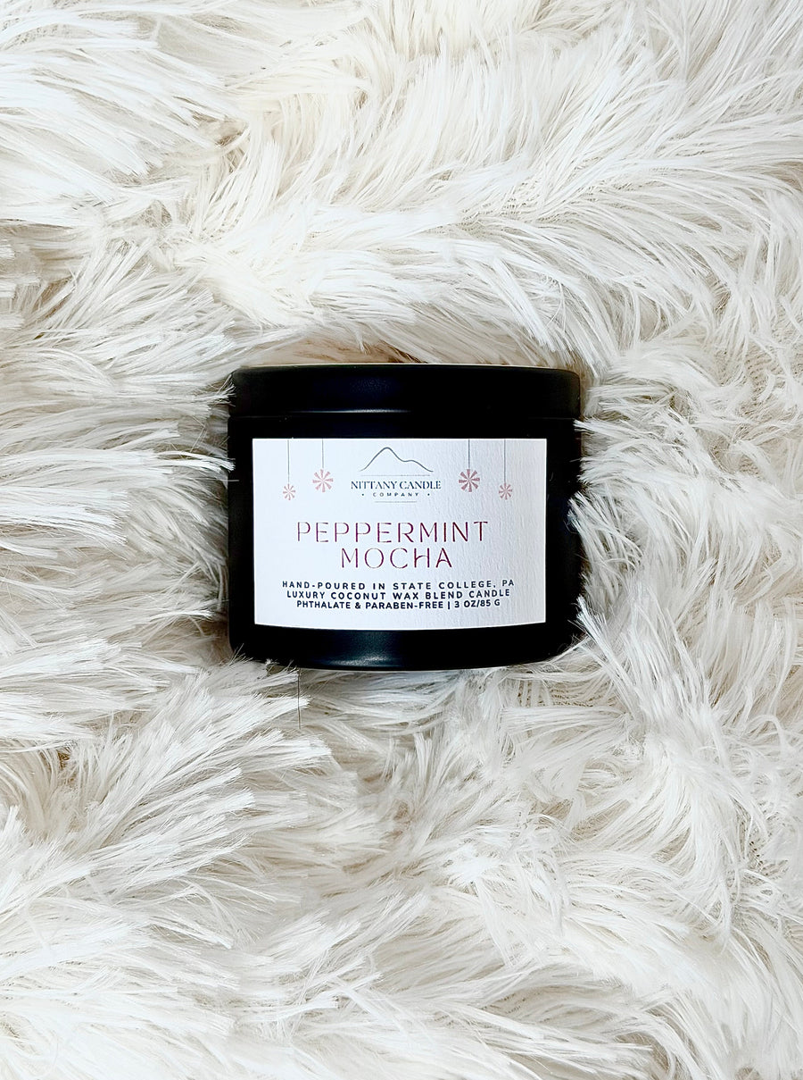 Candle labeled 'Peppermint Mocha' on a fluffy white surface
