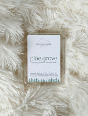 Wax melt packaging labeled 'pine grove' on a fluffy white surface