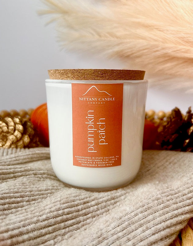 Nittany Candle Company pumpkin patch wood wick candle with a cork lid on a textured surface.