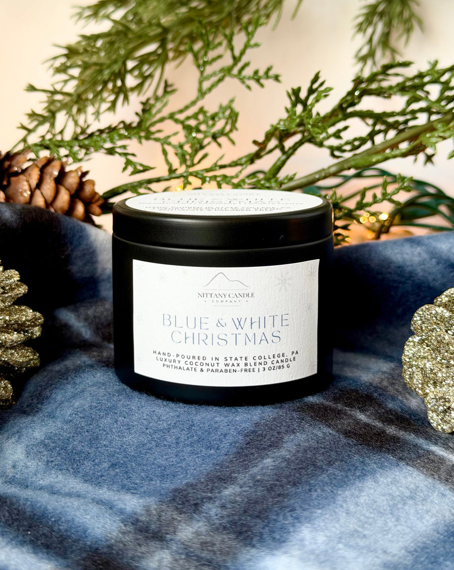 Penn State themed candle labeled 'Blue & White Christmas' on a blue fabric background with decorative elements.