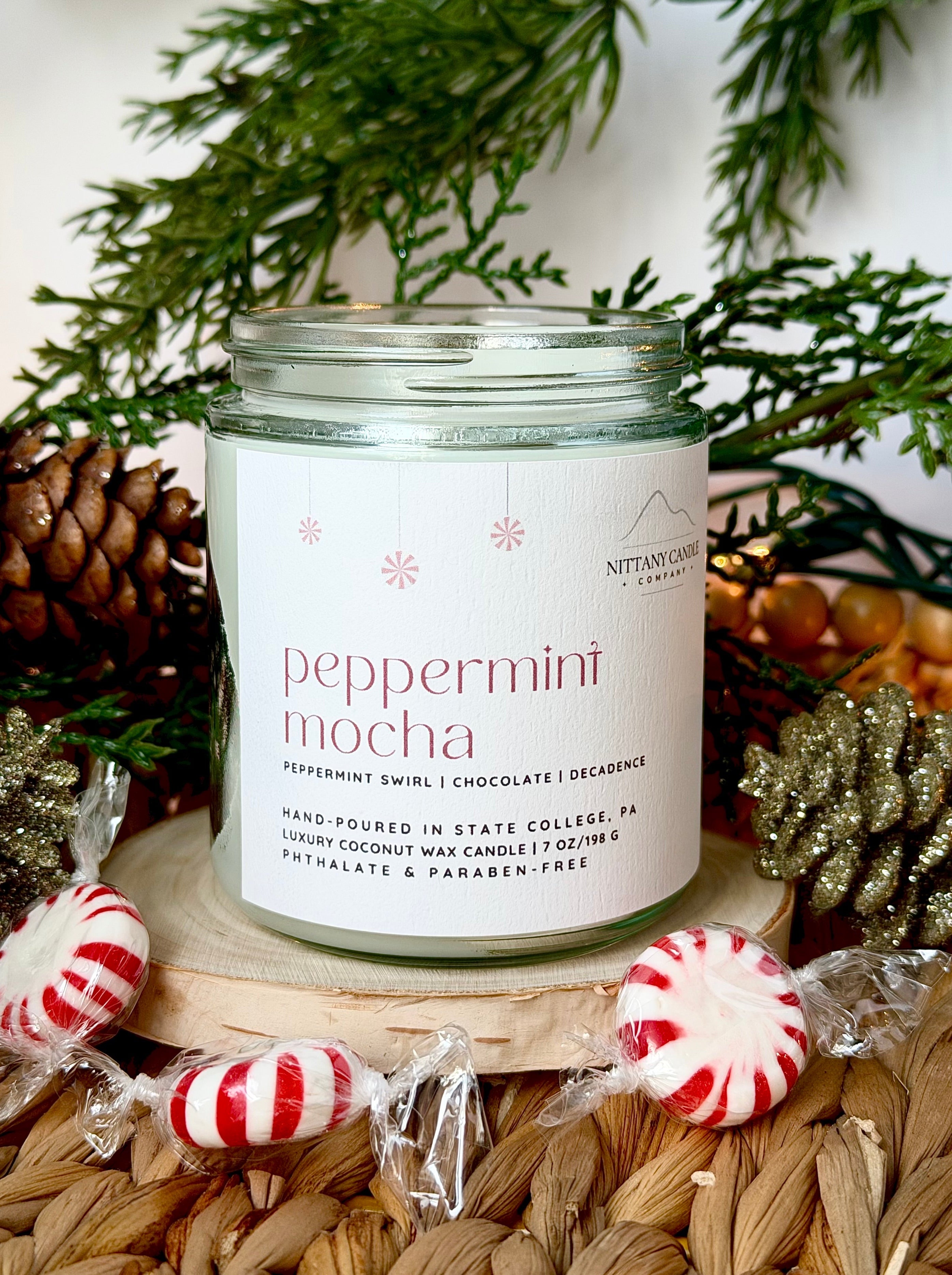Candle labeled 'Peppermint Mocha' with Christmas decorations in the background