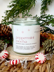 Candle labeled 'Peppermint Mocha' with Christmas decorations in the background