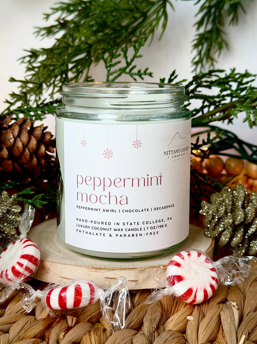 Candle labeled 'Peppermint Mocha' with Christmas decorations in the background