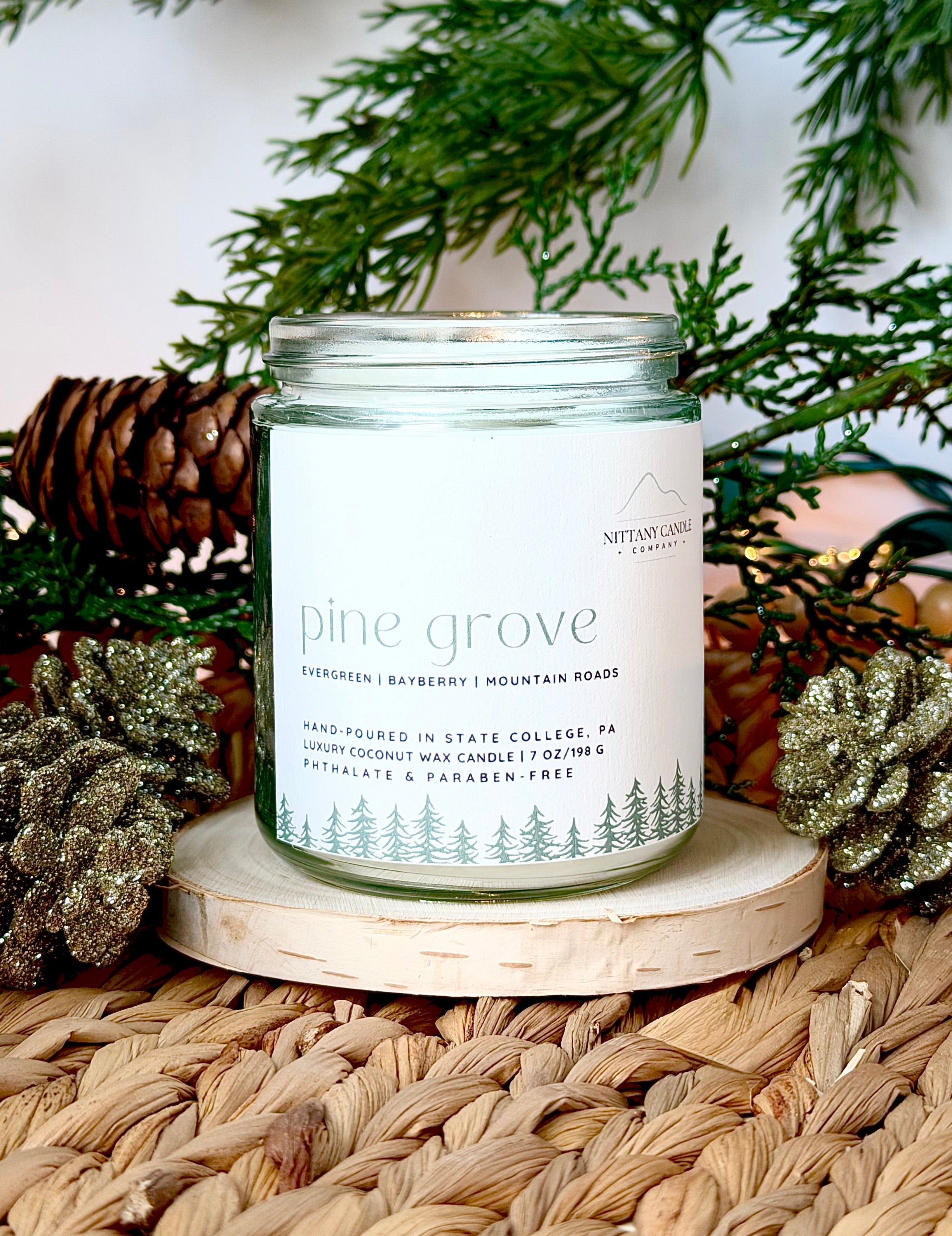 Nittany Candle Company candle labeled 'Pine Grove' on a woven surface with decorative elements.