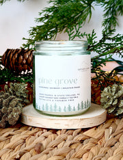 Nittany Candle Company candle labeled 'Pine Grove' on a woven surface with decorative elements.