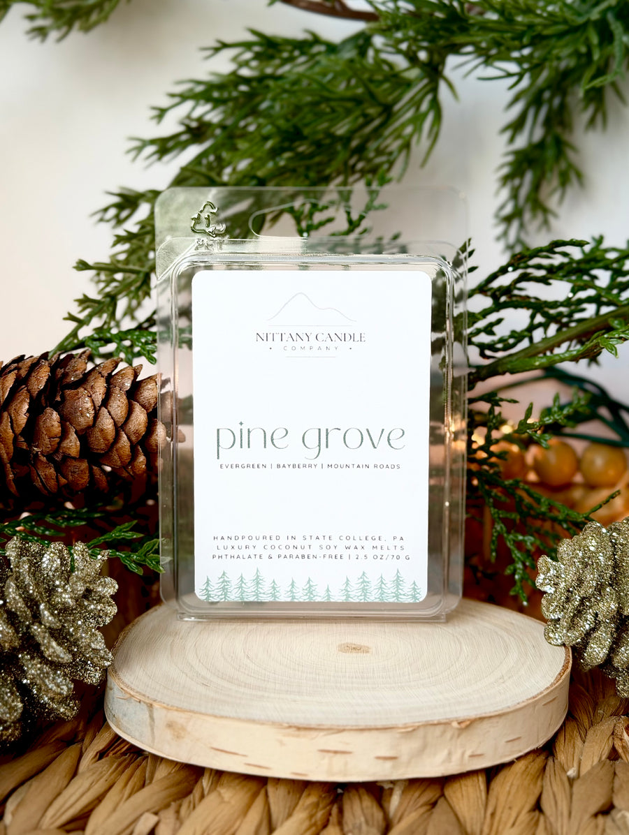 Non-toxic wax melts labeled 'pine grove' with decorative greenery and pinecones in the background