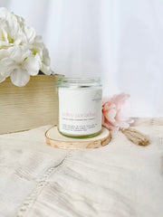 Candle labeled 'Paradise' on a wooden coaster with flowers in the background