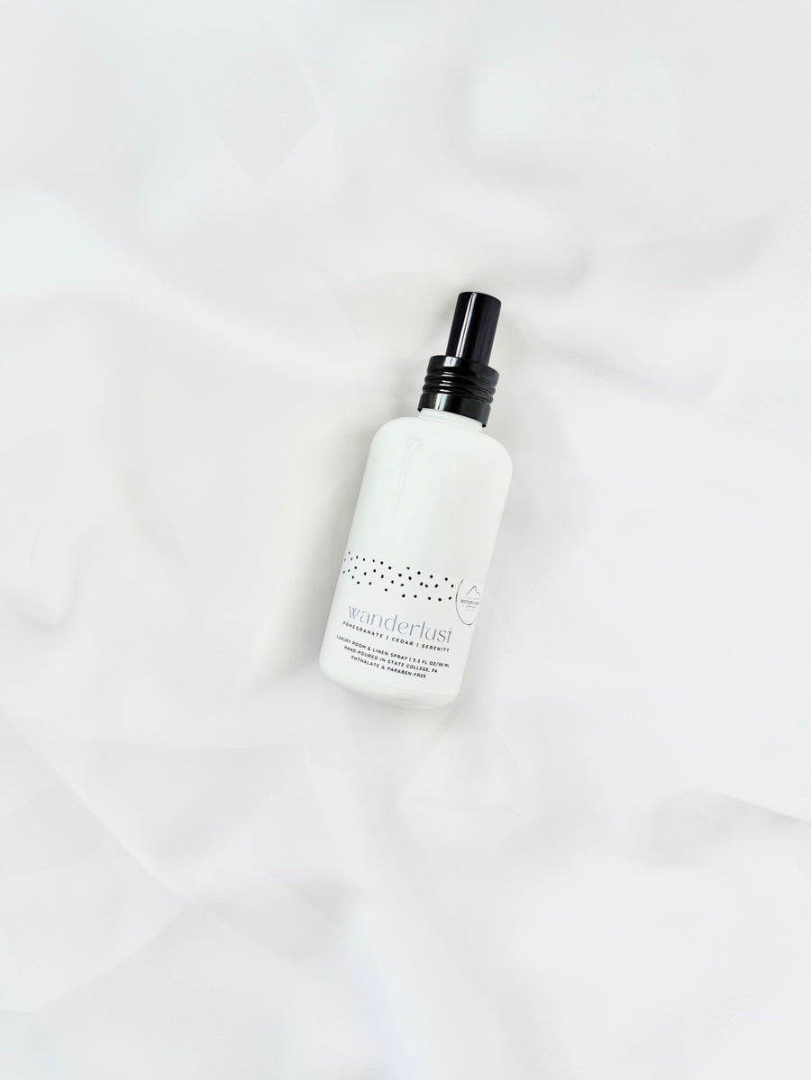 Wanderlust linen spray bottle with black cap on white fabric background