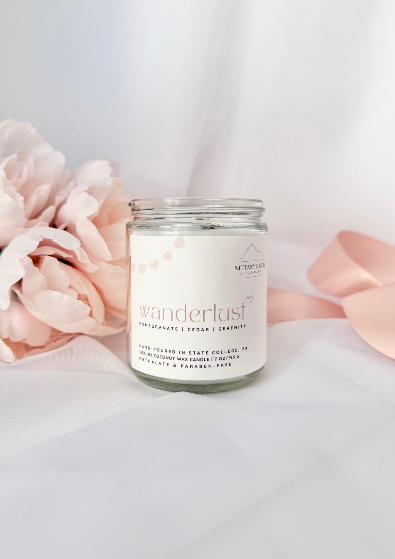 Nittany Candle Company Wanderlust candle with pink flowers and a ribbon on a light background