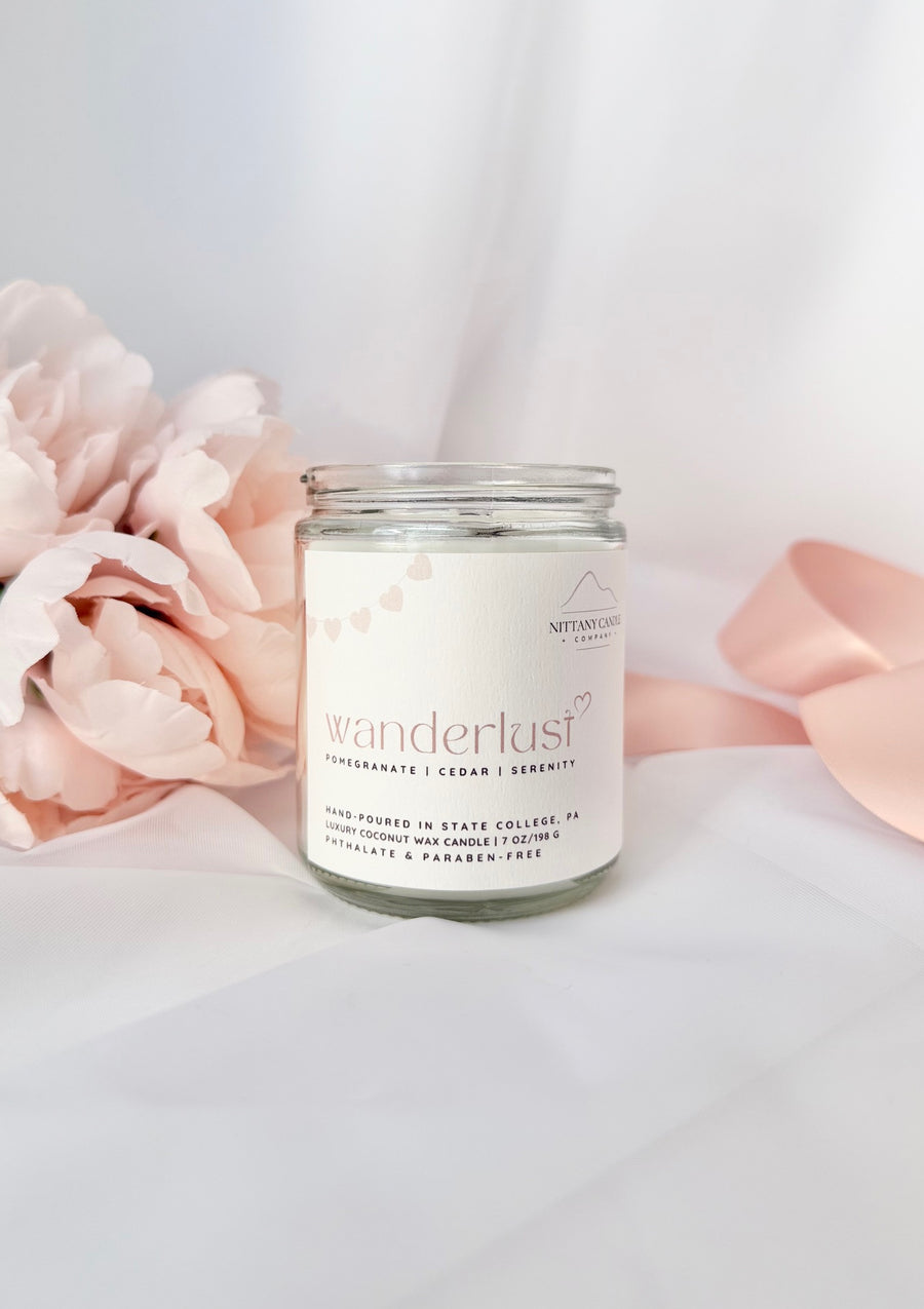 Nittany Candle Company Wanderlust candle with pink flowers and a ribbon on a light background