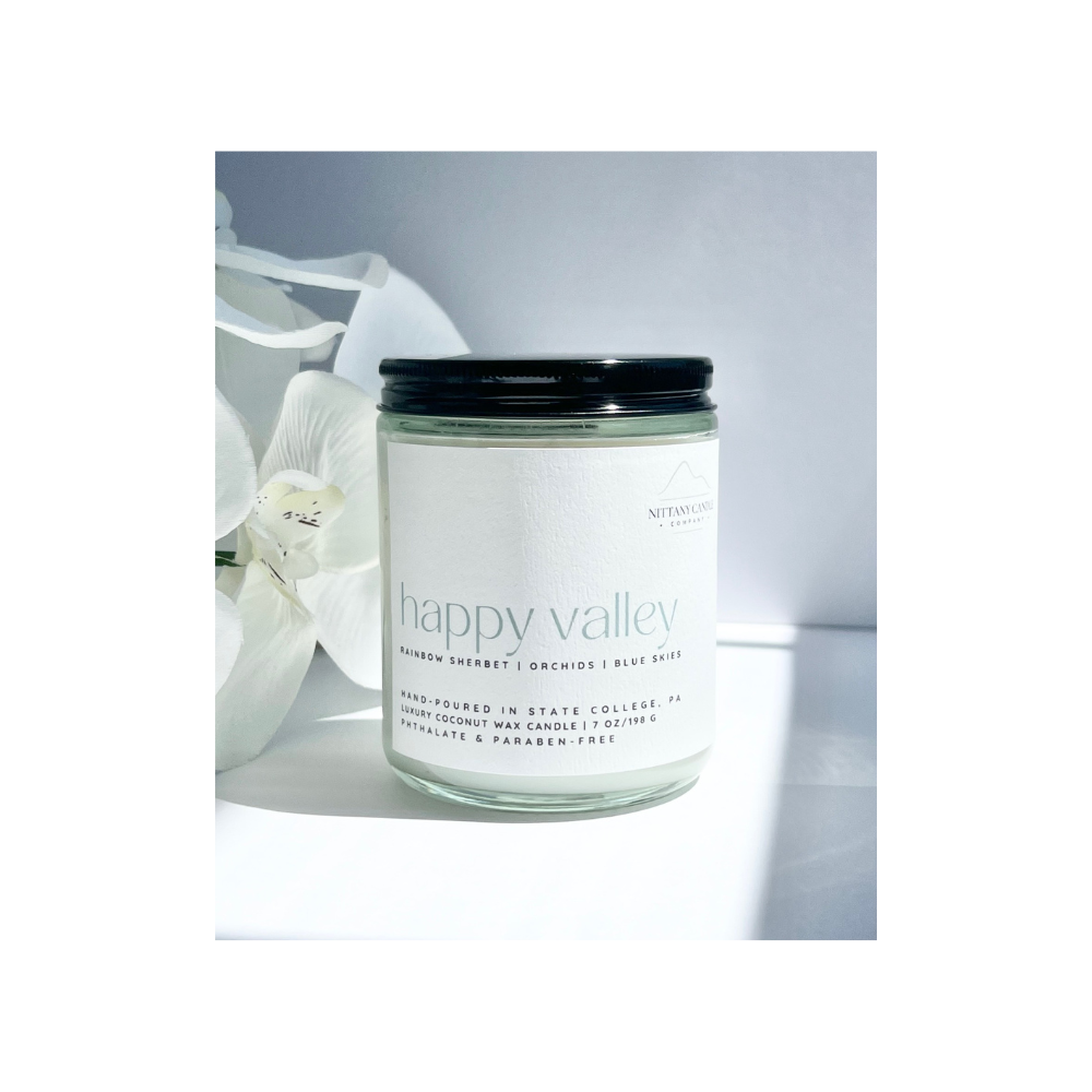 Candle jar labeled 'happy valley' with a white flower in the background